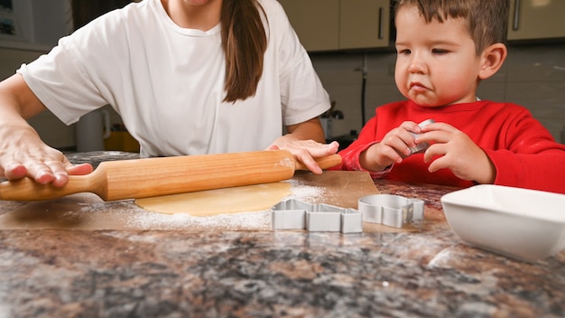 ママと子供はクッキーのために生地を転がします