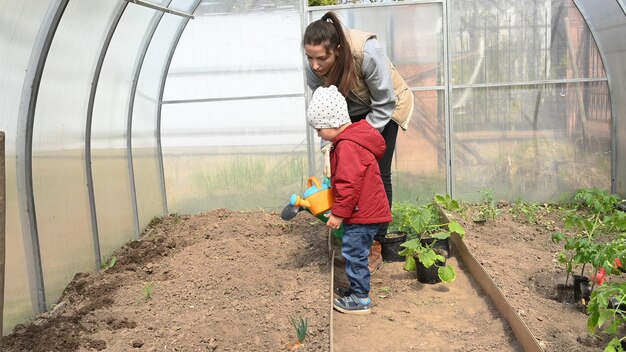 Mom and child take care of plants in the greenhouse.