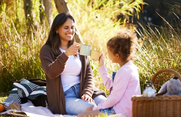 mom child and toast together for outdoor picnic with coffee drink summer and bonding in nature mama young girl and cheers with espresso cup love relationship and happy family on grassy field