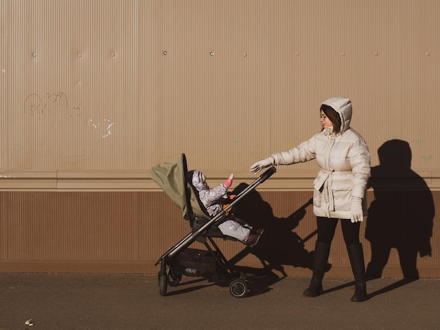 Mamma e bambino camminano in inverno con un passeggino