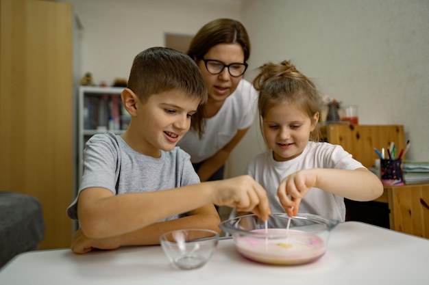 Mom and children are having fun at home experimenting with milk and paints