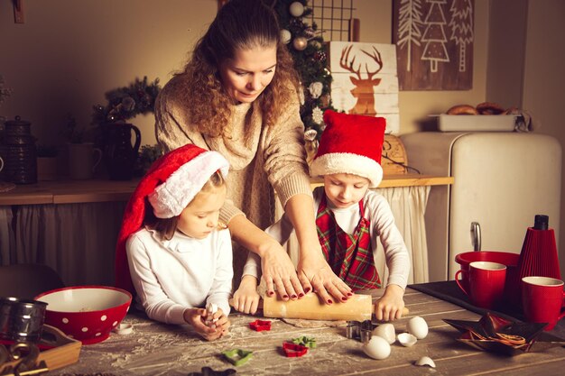 Foto la mamma e i bambini stanno preparando i biscotti in cucina decorazioni natalizie tradizioni familiari cibo natalizio vigilia delle vacanze