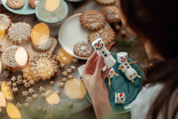 Mom and children decorate christmas gingerbread at home a boy and a girl paint with cornets with sug...