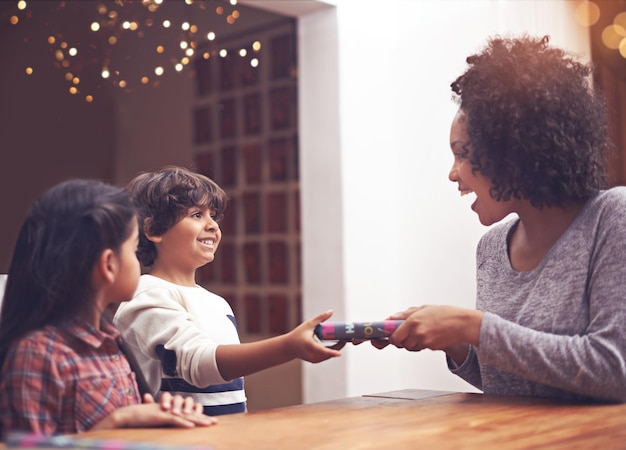 Photo mom children and happy in table with gift as birthday present with smile support and bonding home family and excited together in living room for childhood memories care for love and siblings