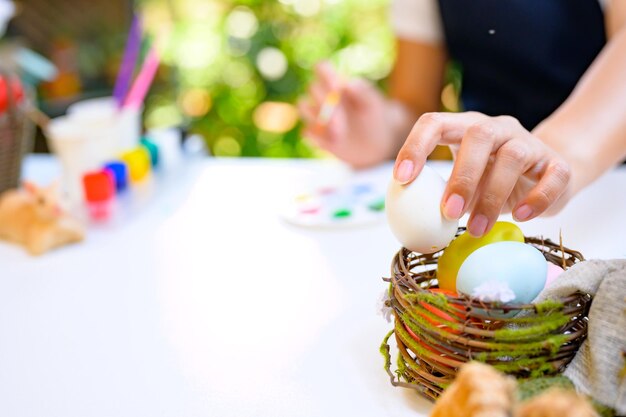 Foto mamma che colora le uova per la celebrazione di pasqua ad aprile. preparazione e pittura per la decorazione della casa di famiglia.