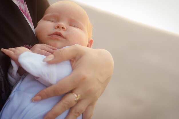 写真 母親は通りで立っている新生児を抱きしめ子供は母親の腕の中で眠っています