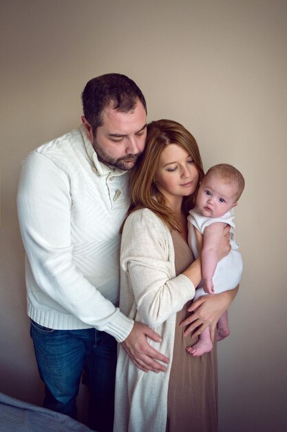 Foto mamma e papà sono in piedi con il bambino al muro della casa alla finestra