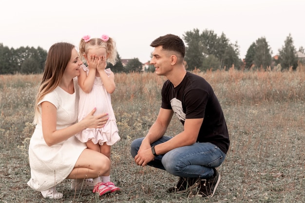 Foto mamma, papà, figlia nel prato. famiglia felice in natura.