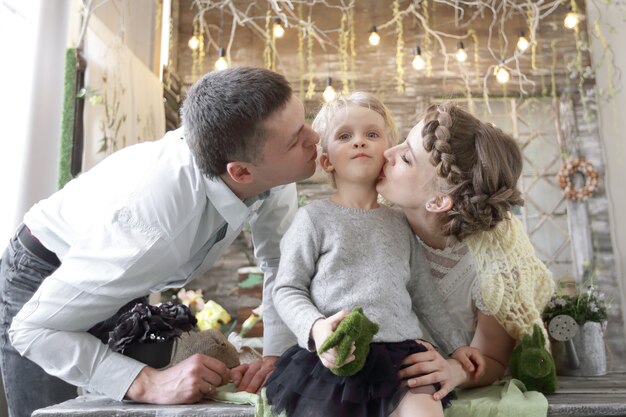 Mom and dad kissing his little daughter