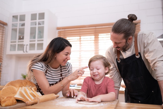 Мама и папа на кухне дома со своими маленькими детьми весело пекут хлеб
