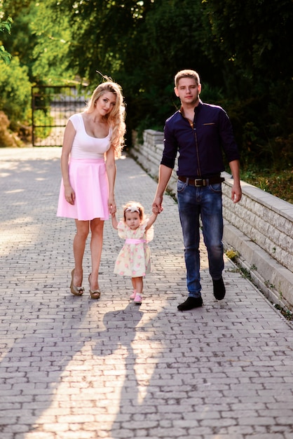 Мама, папа и дочка гуляют по парку. Счастливая семья.