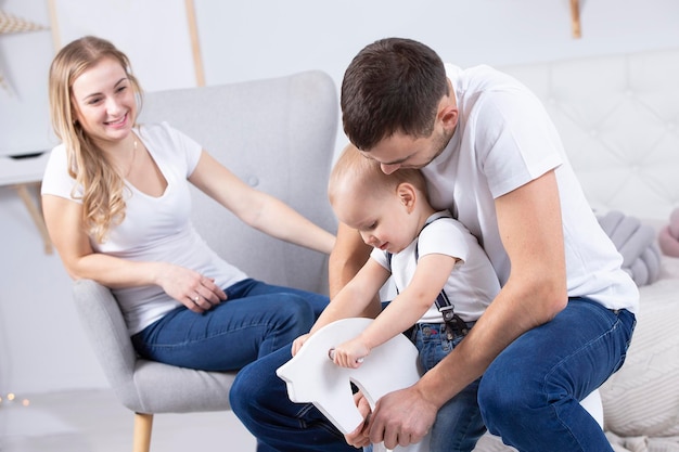 Mom dad and little son are playing at home Young family with a child