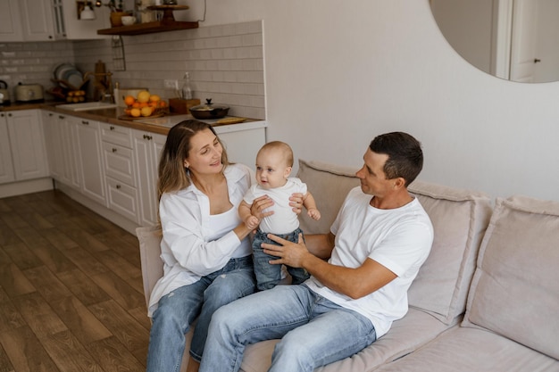 mom and dad play on the couch with their son near the big windows