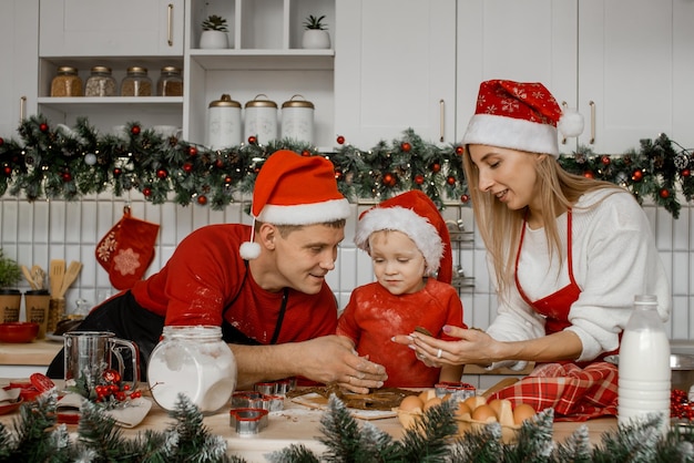 Mom dad and son in the kitchen prepare gingerbread cookies for Christmas Happy family on vacation