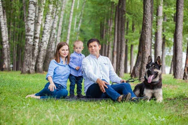 Mom, dad and son on a walk with a shepherd dog in the forest