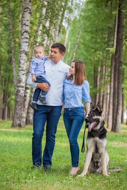 Mom, dad and son on a walk with a shepherd dog in the forest