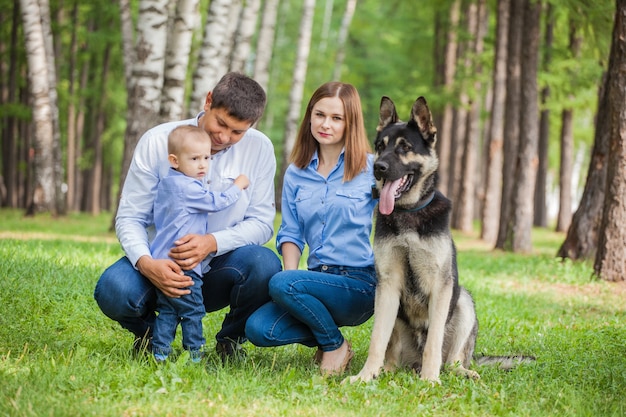 Mom, dad and son on a walk with a shepherd dog in the forest