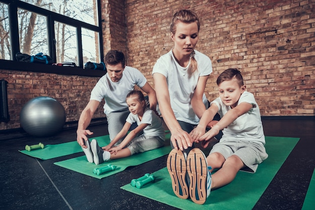 Mom and Dad teaches children stretching in the gym