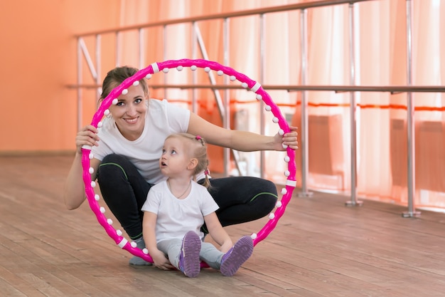 Mom and daughter are engaged in sports with a hoop.