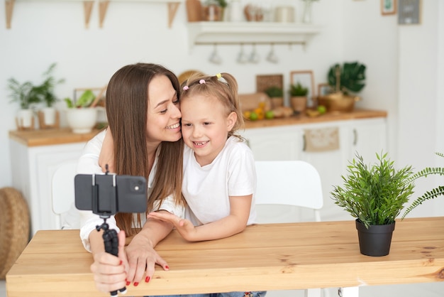 Mom and daughter are having fun and fooling around while recording a video blog. Lifestyle. Spending time with your family.