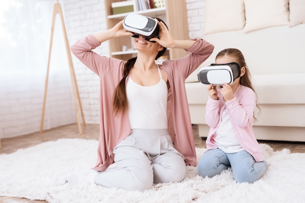 Mom and daughter are looking into virtual reality glasses.