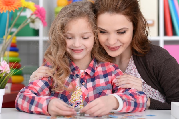 Mom and daughter are playing at the table in the room