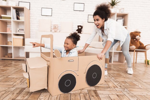 Mom and daughter are playing with big toy cars.