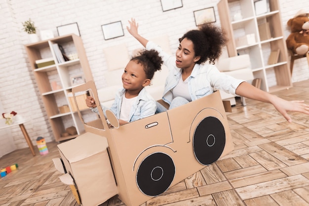 Mom and daughter are playing with big toy cars.