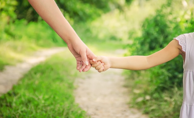 Mom and daughter are walking along the road holding hands.