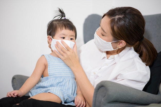 Mom and daughter are wearing protective mask at home