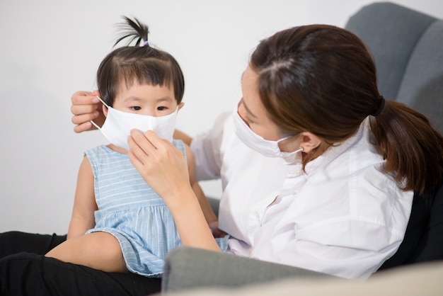 Mom and daughter are wearing protective mask at home