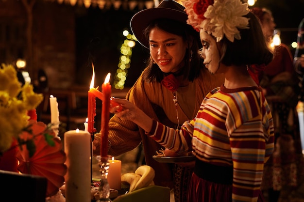 Photo mom and daughter celebrating the holiday together they lighting candles at altar