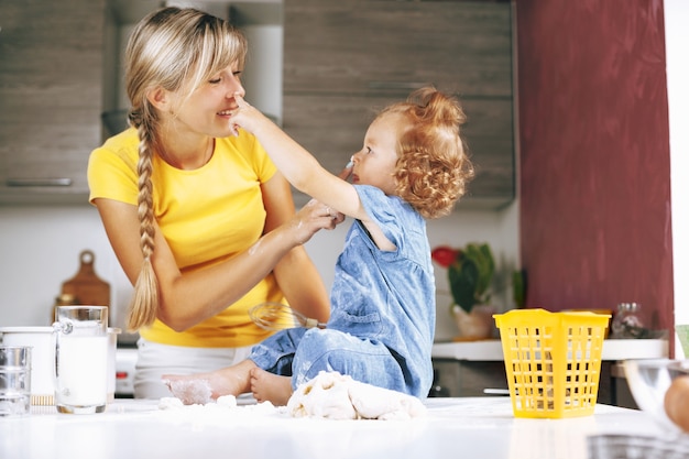 Mom and daughter cooking in the kitchen, smiling and playing