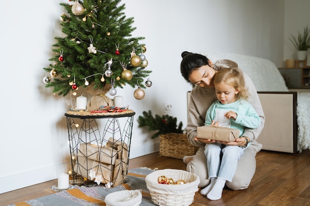 ママと娘が部屋のクリスマスツリーを飾ります。メリークリスマスと新年あけましておめでとうございますのコンセプト。テキスト用のスペース。家族の居心地の良い瞬間。