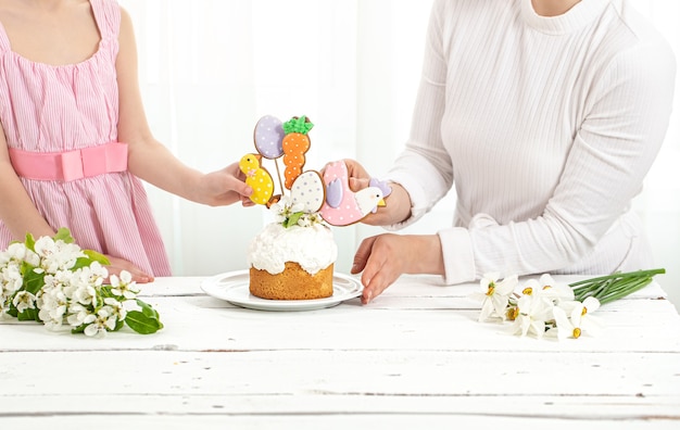 Mom and daughter decorate the pakhsal cake. The concept of preparing for the family holiday Easter.