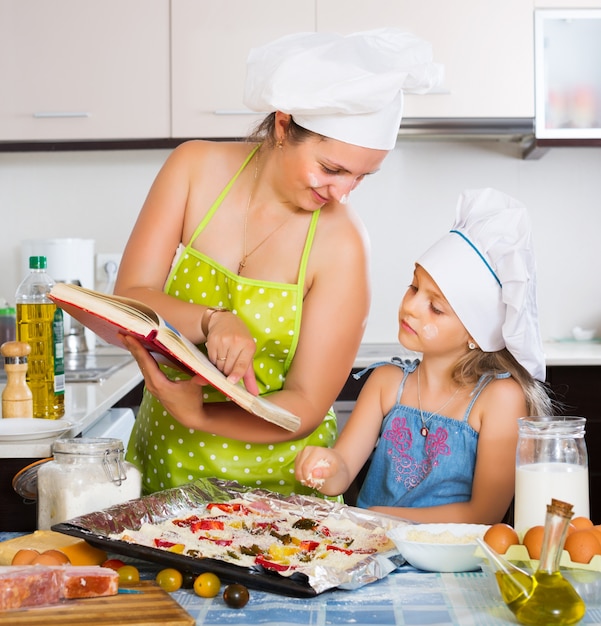 Photo mom and daughter decorating pizza