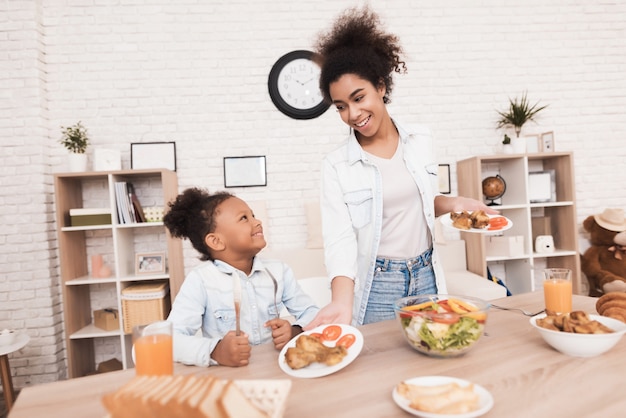 Mom and daughter eat together in the kitchen.