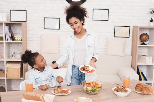 Mom and daughter eat together in the kitchen.