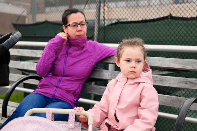 Photo mom and daughter enjoing a day on the boardwalk with baby strollers toy and real