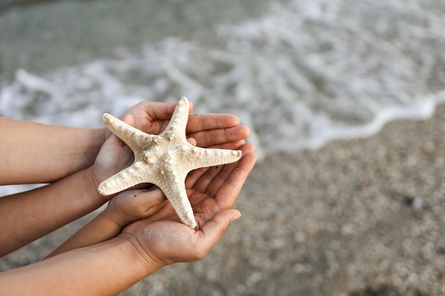 Mom and daughter in the hands holding a starfish on a background of the sea