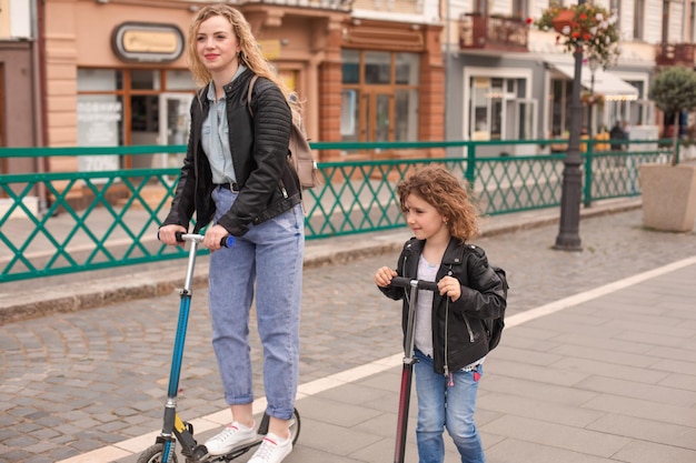 The mom and daughter have fun riding scooters