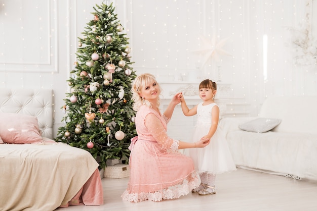 Mom and daughter at home on the background of a christmas tree