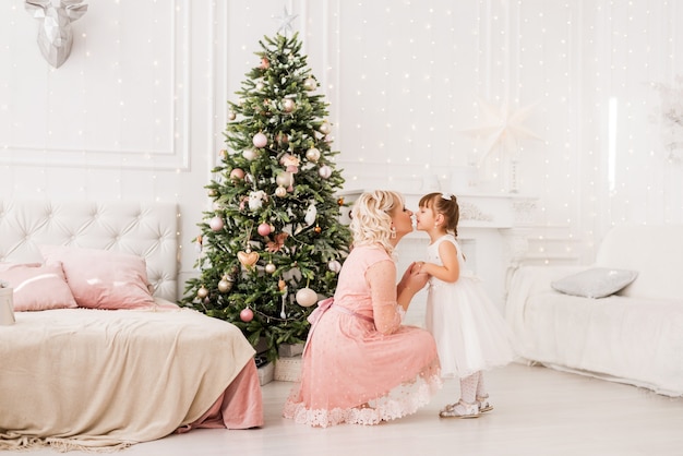 Mom and daughter at home on the background of a Christmas tree