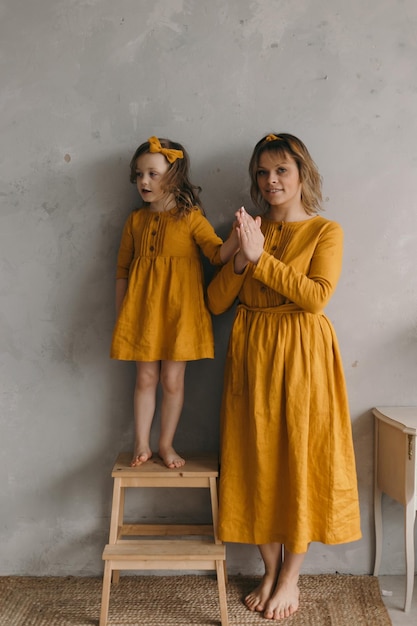 Mom and daughter in linen dresses are spinning laughing and having fun