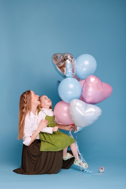 Mom and daughter look at balloons and smile on Mother's Day