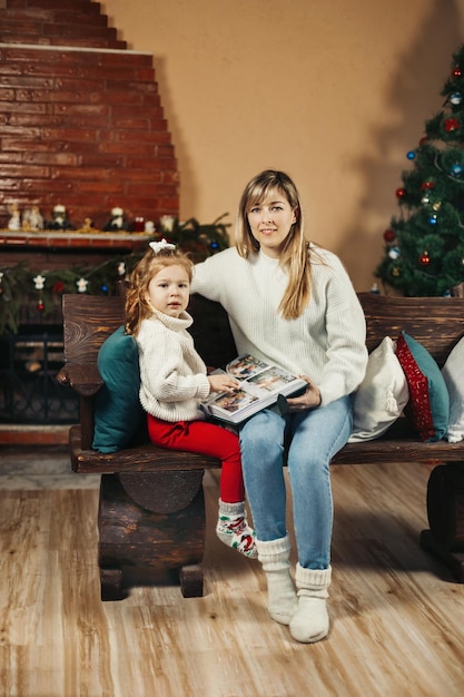 Mom and daughter looking through a family photo album on Christmas Eve