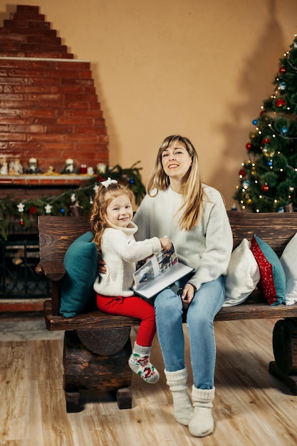 Mom and daughter looking through a family photo album on Christmas Eve