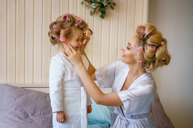 Мама и дочка делают макияж друг другу, счастливые семейные отношения