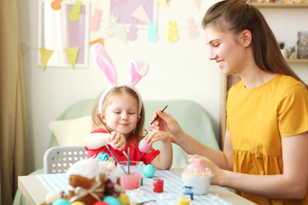 Mom and daughter paint easter eggs for the holiday easter traditions