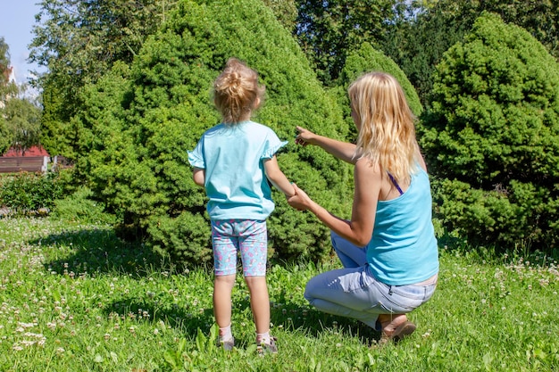 夏の公園でお母さんと娘 夏に公園で散歩する小さな女の子とお母さん